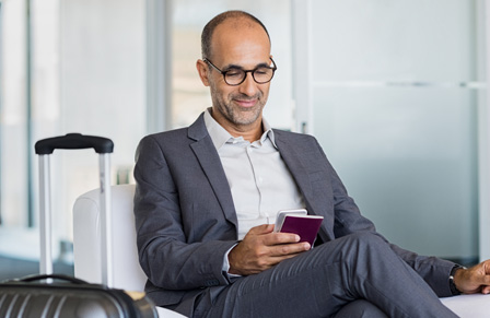 Business traveler sitting in airport lounge holding phone and passport