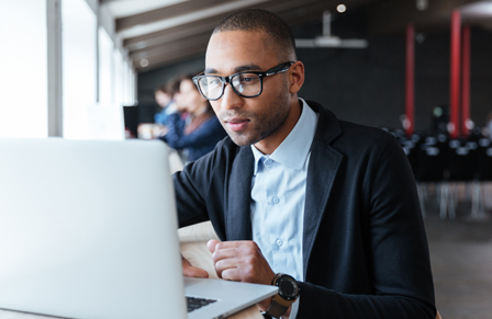 Business man in glasses using travel forecasting technology on laptop