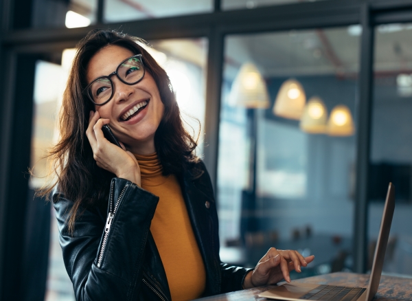 Smiling woman seated at desk talking on cell phone